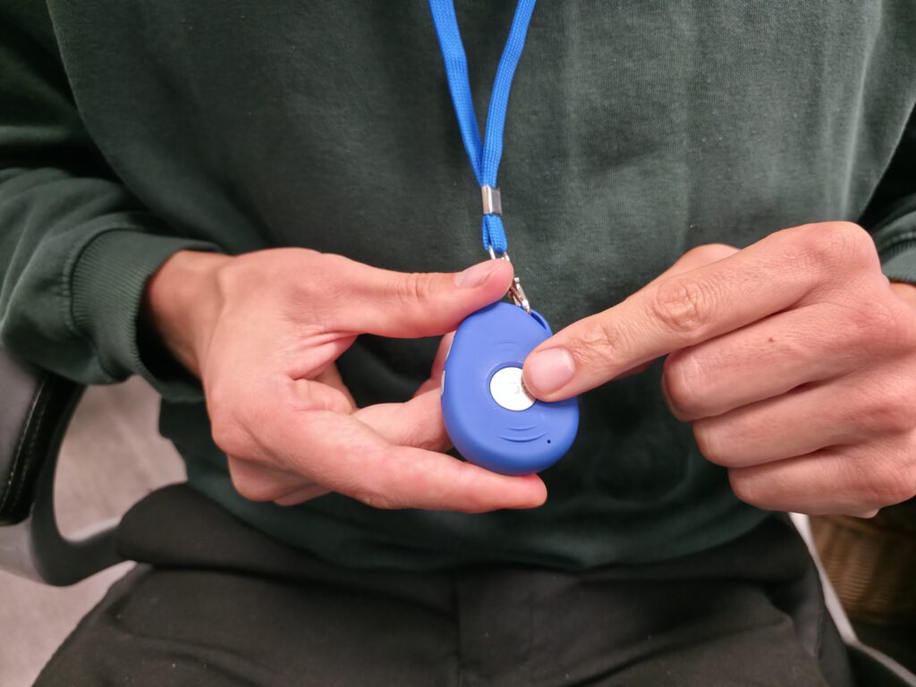Het blauwe seniorenalarm aan een koord, gedragen om de nek